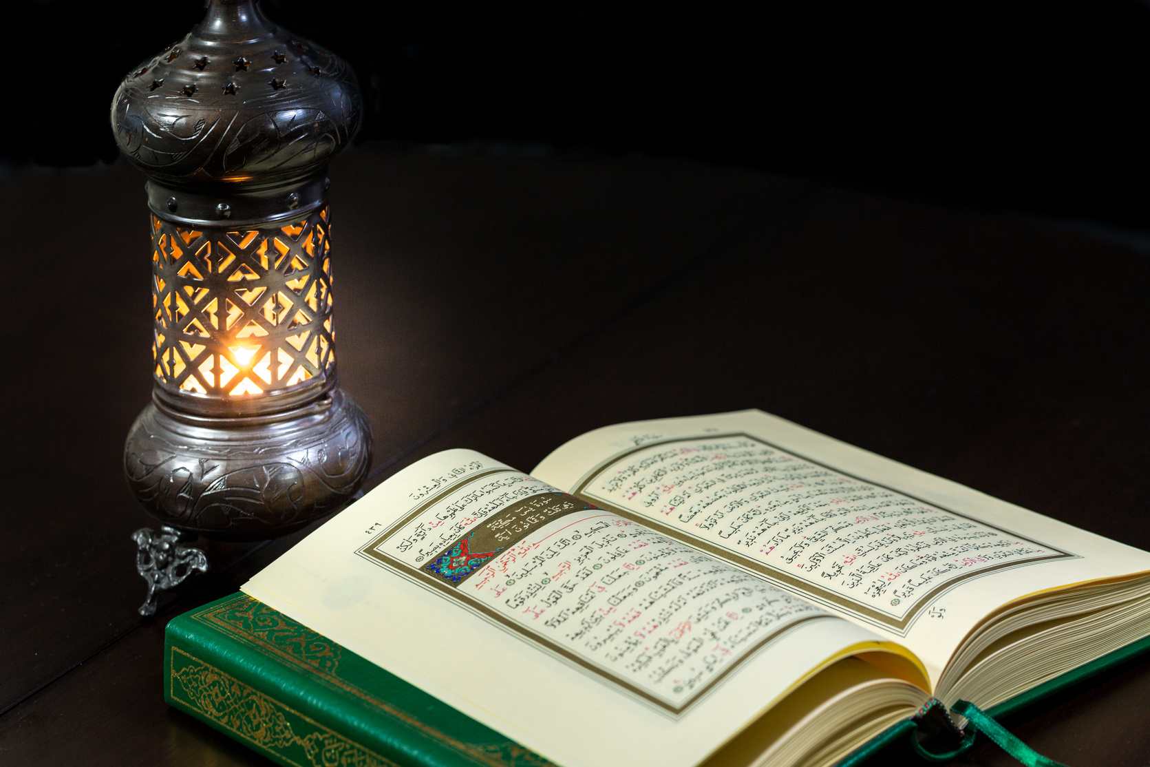 Pages of holy book Qur'an with vintage lamp and dark background